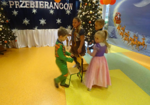 Czworo dzieci tańczy wokół rozstawionych w kole krzeseł.